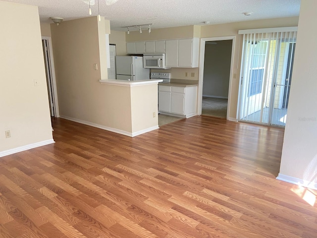 kitchen featuring track lighting, baseboards, light wood finished floors, and white appliances