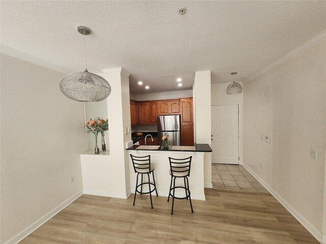 2528 Robert Trent Jones Dr Unit 1617, Orlando, FL 32835 - kitchen featuring dark countertops, freestanding refrigerator, a kitchen breakfast bar, a textured ceiling, and light wood finished floors