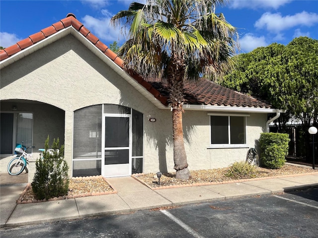 view of front facade with uncovered parking, stucco siding, and a tiled roof
