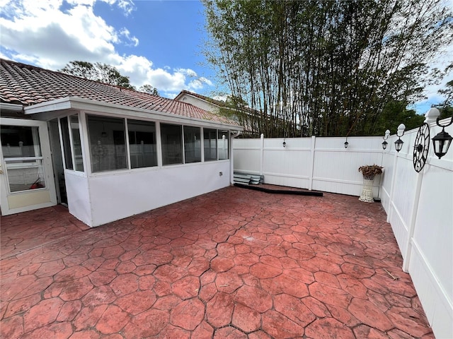 view of patio featuring a fenced backyard and a sunroom
