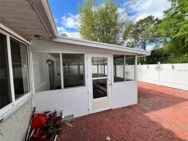 view of patio / terrace featuring a sunroom and fence
