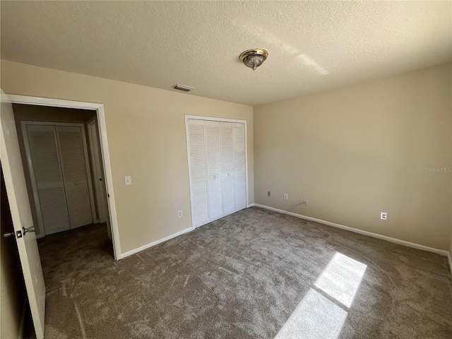 unfurnished bedroom featuring a closet, carpet flooring, a textured ceiling, and visible vents