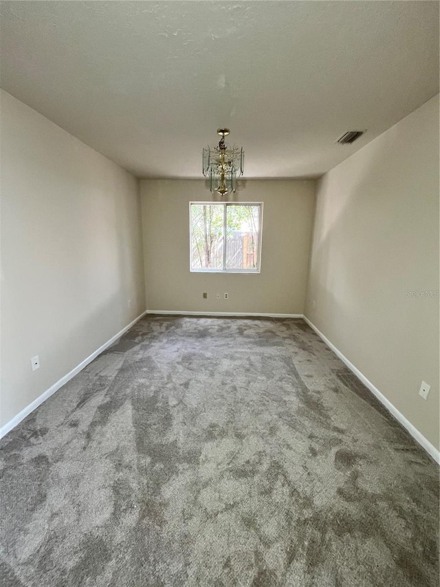 unfurnished dining area featuring baseboards, carpet flooring, a chandelier, and visible vents