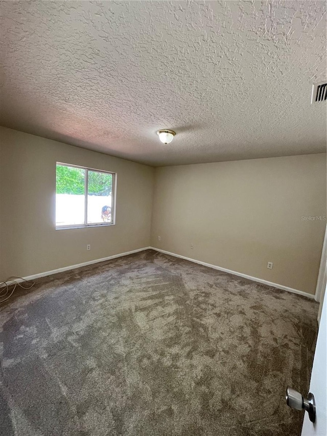 carpeted empty room featuring a textured ceiling, baseboards, and visible vents