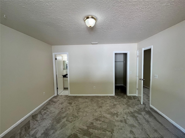 unfurnished bedroom with a closet, baseboards, a walk in closet, connected bathroom, and carpet flooring