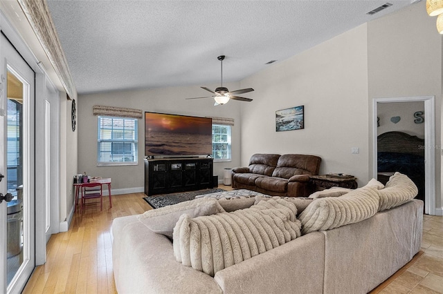 living area featuring visible vents, vaulted ceiling, a ceiling fan, and a healthy amount of sunlight