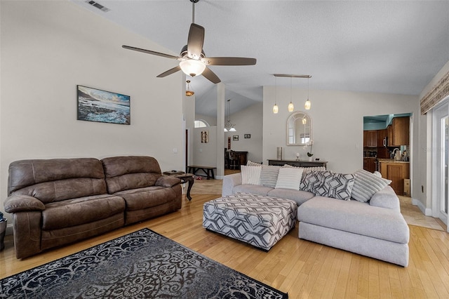 living room featuring light wood finished floors, visible vents, a ceiling fan, and lofted ceiling
