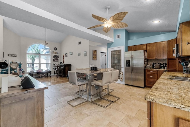 kitchen featuring visible vents, a sink, ceiling fan, stainless steel appliances, and decorative backsplash