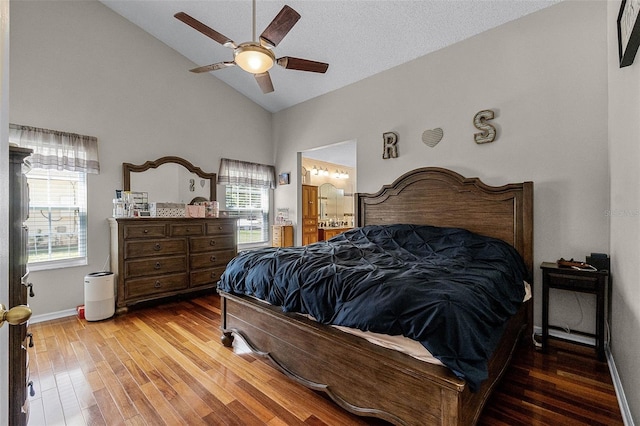 bedroom with ensuite bathroom, ceiling fan, high vaulted ceiling, wood finished floors, and baseboards