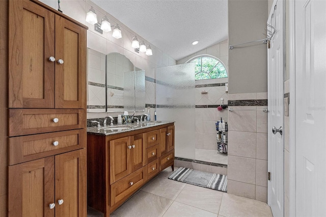 bathroom featuring a sink, tile walls, a textured ceiling, a walk in shower, and double vanity