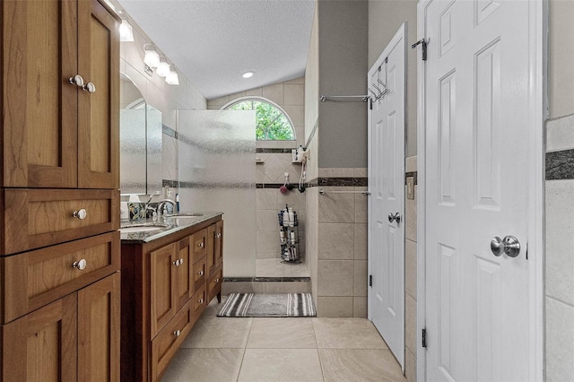 full bathroom with tile walls, a textured ceiling, vanity, tile patterned flooring, and walk in shower