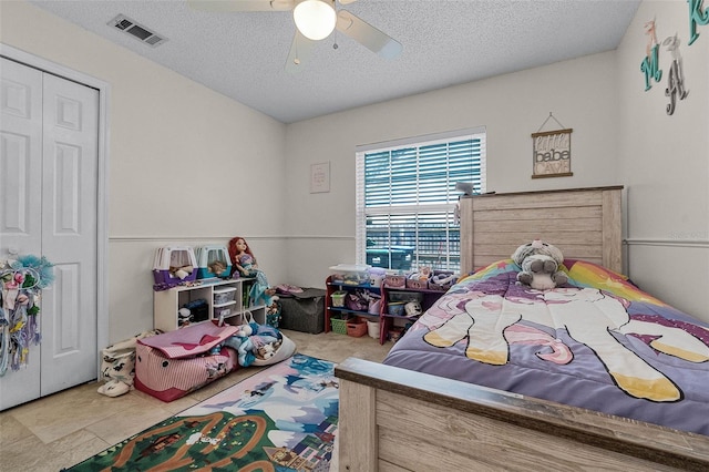 bedroom featuring a textured ceiling, a closet, a ceiling fan, and visible vents