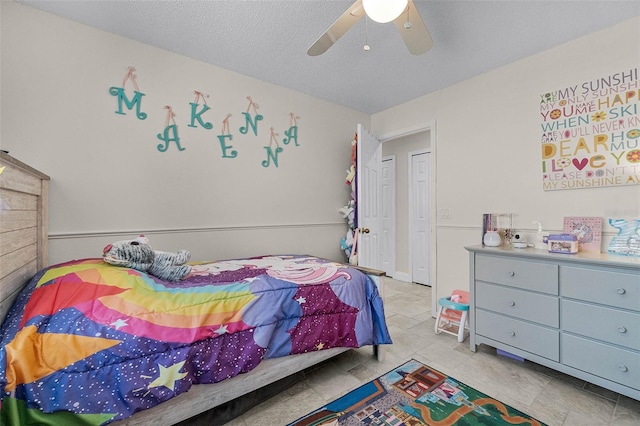 tiled bedroom with a ceiling fan and a textured ceiling