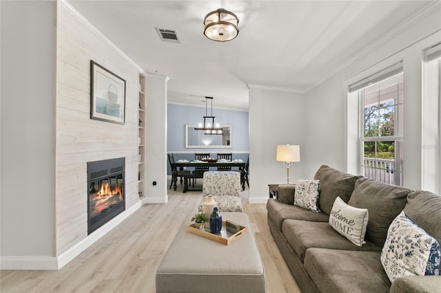 6330 Oil Well Rd, Clermont, FL 34714 - living room with a notable chandelier, light wood-type flooring, a large fireplace, crown molding, and visible vents