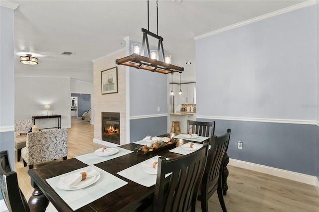 6330 Oil Well Rd, Clermont, FL 34714 - dining area featuring light wood-style flooring, ornamental molding, visible vents, a tile fireplace, and baseboards