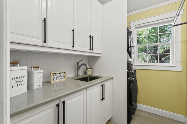 6330 Oil Well Rd, Clermont, FL 34714 - clothes washing area featuring baseboards, ornamental molding, stacked washer and clothes dryer, cabinet space, and a sink