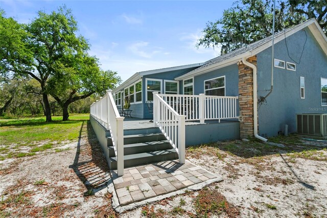 6330 Oil Well Rd, Clermont, FL 34714 - back of house featuring central AC unit, stucco siding, a wooden deck, and a shingled roof