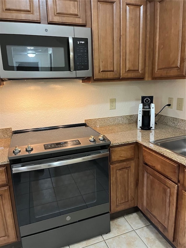 12527 Floridays Resort Dr Unit 311E, Orlando, FL 32821 - kitchen with brown cabinets, appliances with stainless steel finishes, and light tile patterned flooring