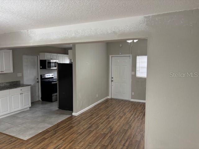 160 S Oxalis Dr, Orlando, FL 32807 - kitchen featuring a textured ceiling, white cabinetry, wood finished floors, stainless steel appliances, and baseboards