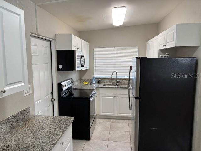160 S Oxalis Dr, Orlando, FL 32807 - kitchen featuring light stone countertops, white cabinets, appliances with stainless steel finishes, light tile patterned flooring, and a sink