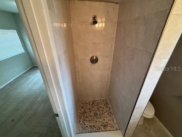 160 S Oxalis Dr, Orlando, FL 32807 - bathroom with baseboards, a tile shower, and toilet