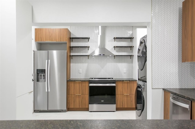 kitchen featuring modern cabinets, wall chimney range hood, open shelves, stacked washer / dryer, and stainless steel appliances
