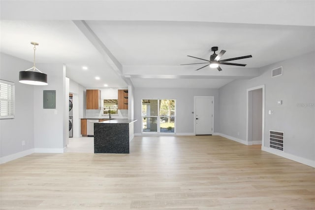 unfurnished living room featuring stacked washer and dryer, visible vents, baseboards, and light wood-style flooring