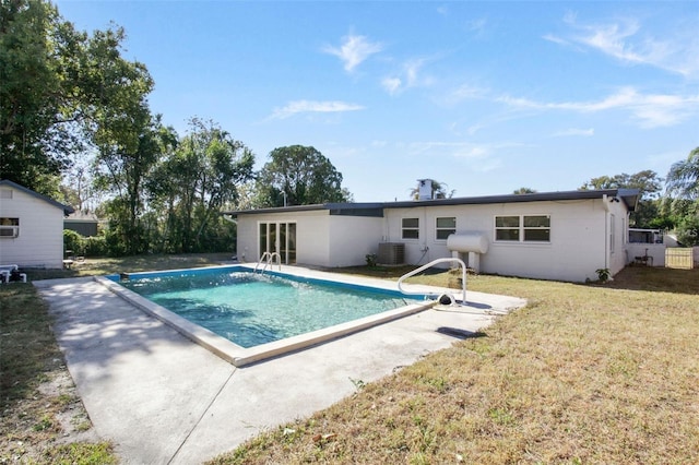 rear view of house with a patio area, an outdoor pool, central AC, and a lawn