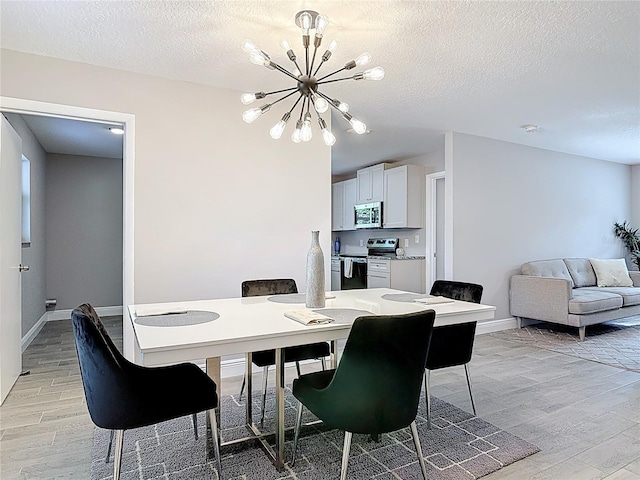 dining room with light wood-type flooring, a textured ceiling, baseboards, and an inviting chandelier