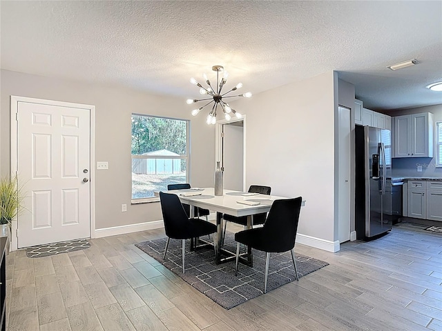dining area featuring a chandelier, a textured ceiling, light wood-style flooring, and visible vents