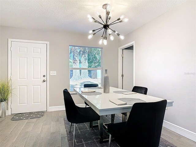 dining room featuring a chandelier, wood finished floors, and a textured ceiling