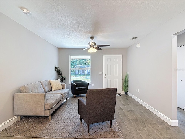living room featuring light wood finished floors, baseboards, a ceiling fan, and visible vents