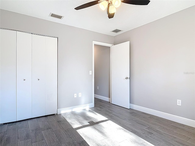 unfurnished bedroom featuring wood finished floors, visible vents, a ceiling fan, a closet, and baseboards