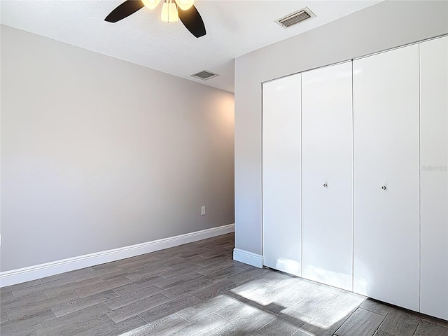 unfurnished bedroom with a closet, wood finished floors, visible vents, and baseboards