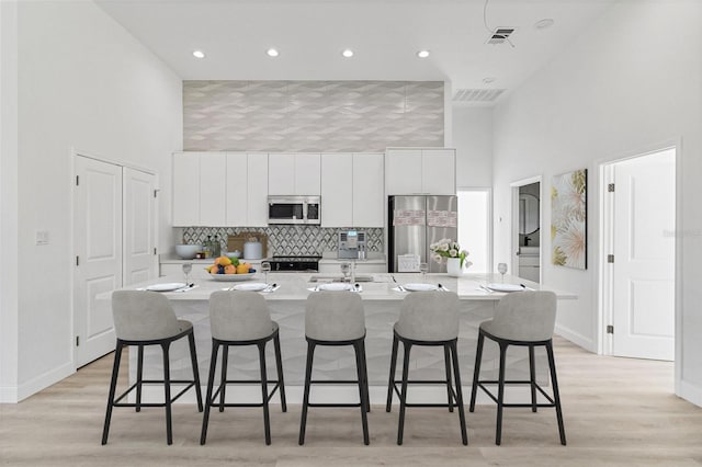 2551 Alhaven Ter, North Port, FL 34286 - kitchen with white cabinets, a kitchen island with sink, a high ceiling, and appliances with stainless steel finishes