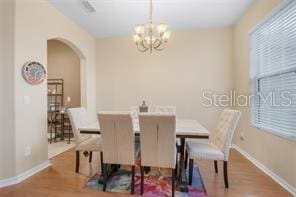 5005 Cape Hatteras Dr, Clermont, FL 34714 - dining space featuring arched walkways, a notable chandelier, baseboards, and wood finished floors