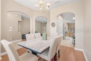 5005 Cape Hatteras Dr, Clermont, FL 34714 - dining area with arched walkways, a notable chandelier, baseboards, and wood finished floors