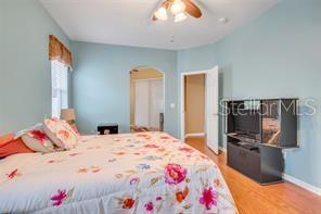 5005 Cape Hatteras Dr, Clermont, FL 34714 - bedroom with baseboards, a ceiling fan, arched walkways, and wood finished floors