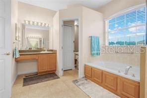 5005 Cape Hatteras Dr, Clermont, FL 34714 - bathroom with a shower with door, tile patterned flooring, vanity, and a garden tub