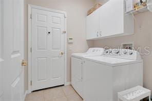 5005 Cape Hatteras Dr, Clermont, FL 34714 - laundry room featuring cabinet space, light tile patterned floors, and separate washer and dryer