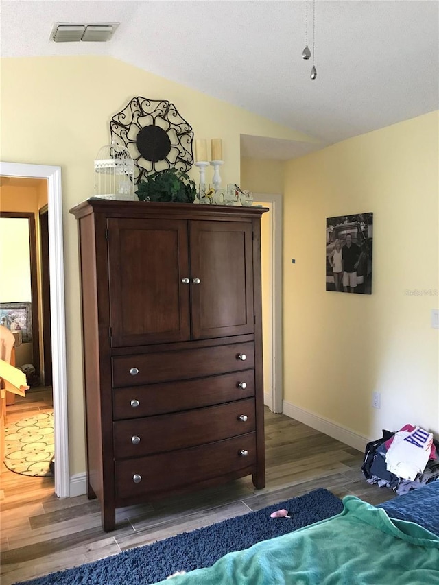 bedroom with visible vents, baseboards, vaulted ceiling, and dark wood finished floors