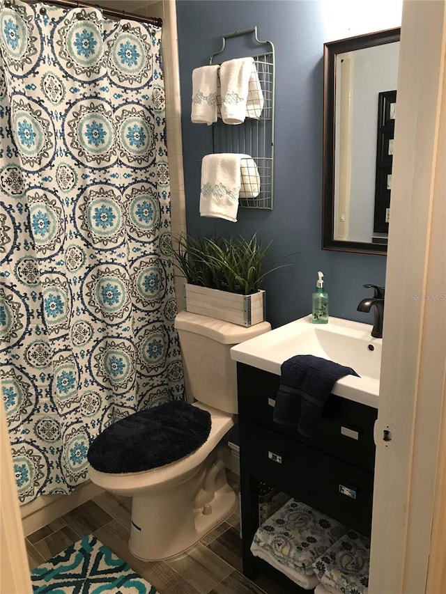 bathroom with toilet, wood finish floors, curtained shower, and vanity
