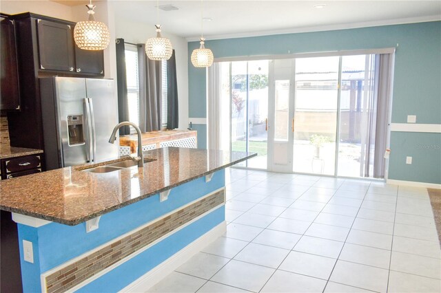 184 Lake Smart Cir, Winter Haven, FL 33881 - kitchen with stainless steel fridge, a sink, a breakfast bar area, dark brown cabinetry, and dark stone counters
