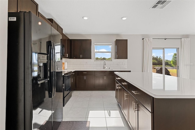 kitchen featuring dark brown cabinetry, visible vents, a sink, light countertops, and black appliances