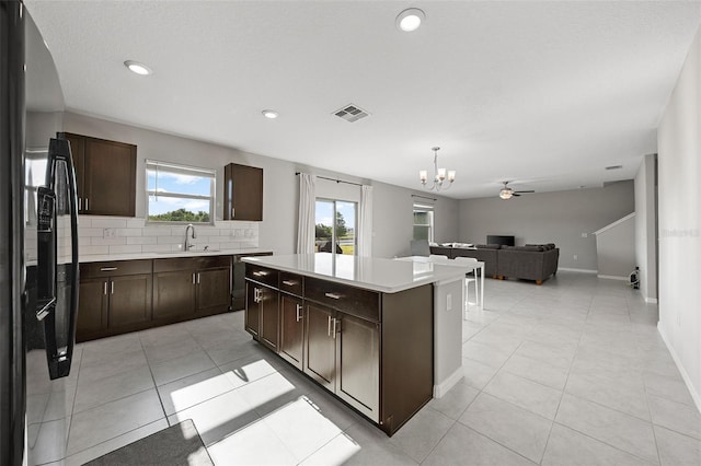 kitchen with visible vents, black refrigerator with ice dispenser, a kitchen island, a sink, and light tile patterned floors