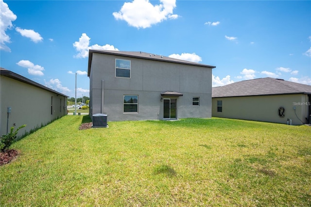 back of property with a yard, central AC unit, and stucco siding