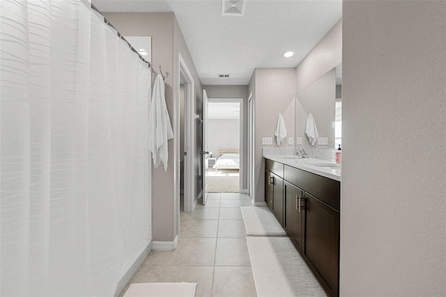 bathroom featuring visible vents, double vanity, baseboards, tile patterned floors, and a sink