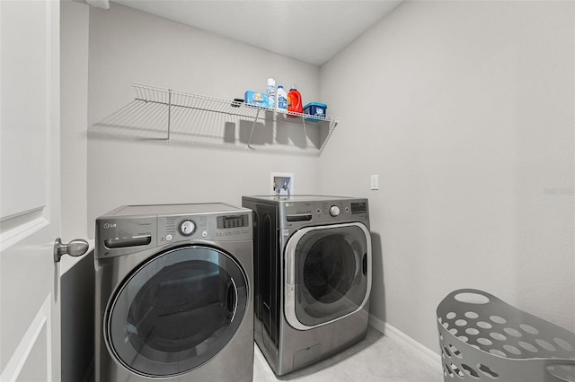 washroom featuring laundry area, baseboards, and washing machine and dryer