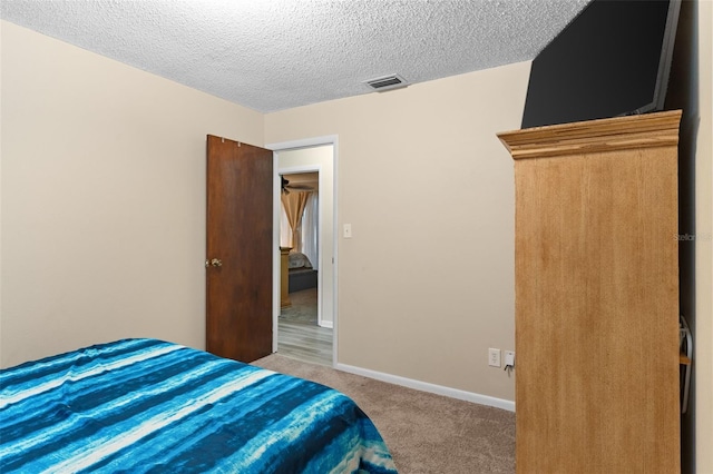 carpeted bedroom with a textured ceiling, baseboards, and visible vents