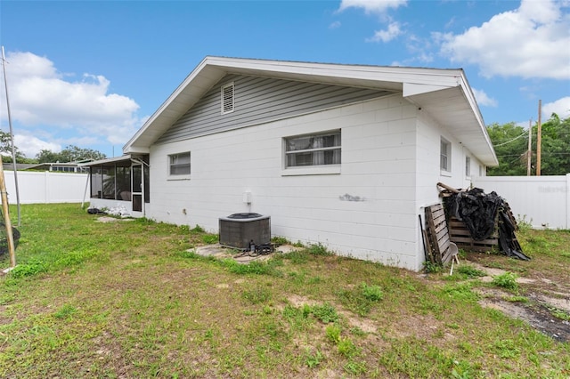 view of home's exterior with a yard, fence, a sunroom, and central air condition unit